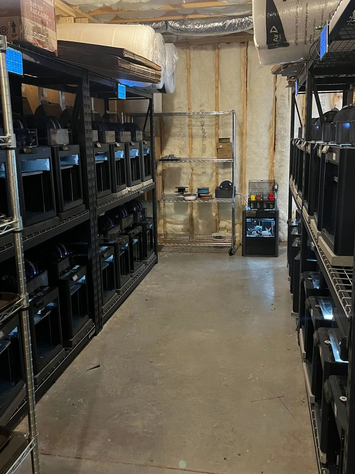 An aisle of Bambu Lab printers at Tabletop Terrain's print farm, managed with SimplyPrint