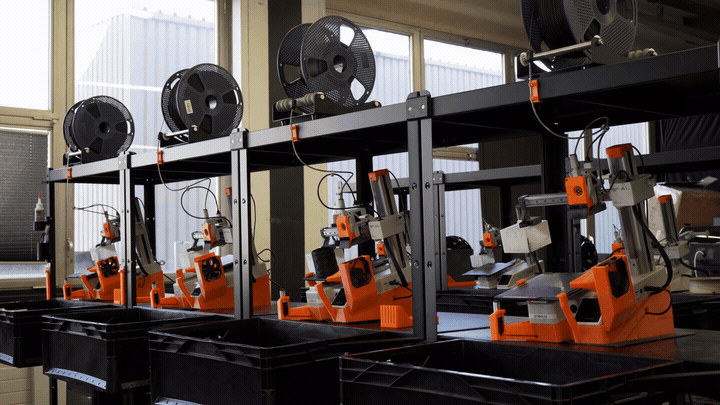 A FarmLoop-automated Bambu Lab print farm at 3D Farmers clearing finished plates and starting the next job automatically