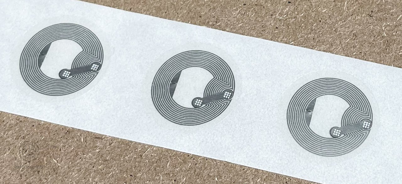 Three round NFC tag inlays on a paper backing strip