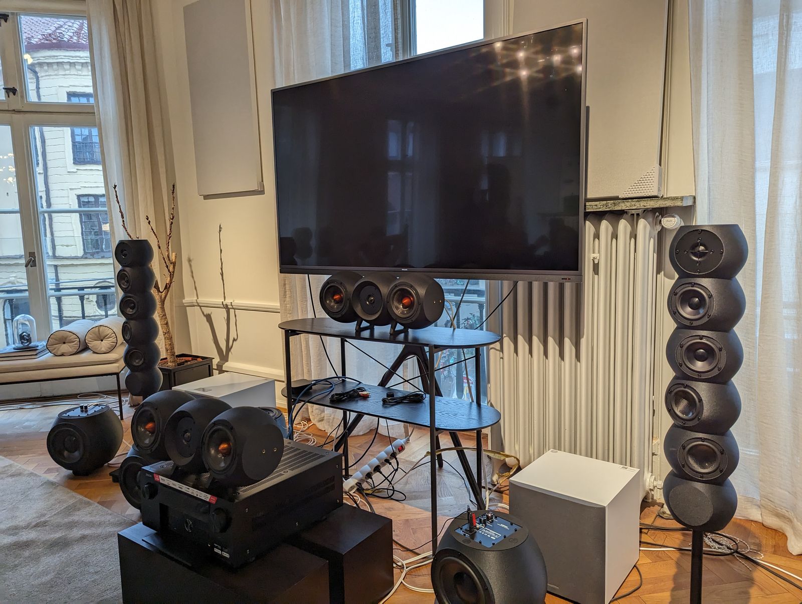 A hi-fi listening room filled with 3D-printed speaker enclosures, towers and subwoofers, around a TV