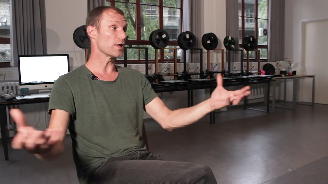 A digital-technology teacher gesturing while talking in the school's 3D printer lab