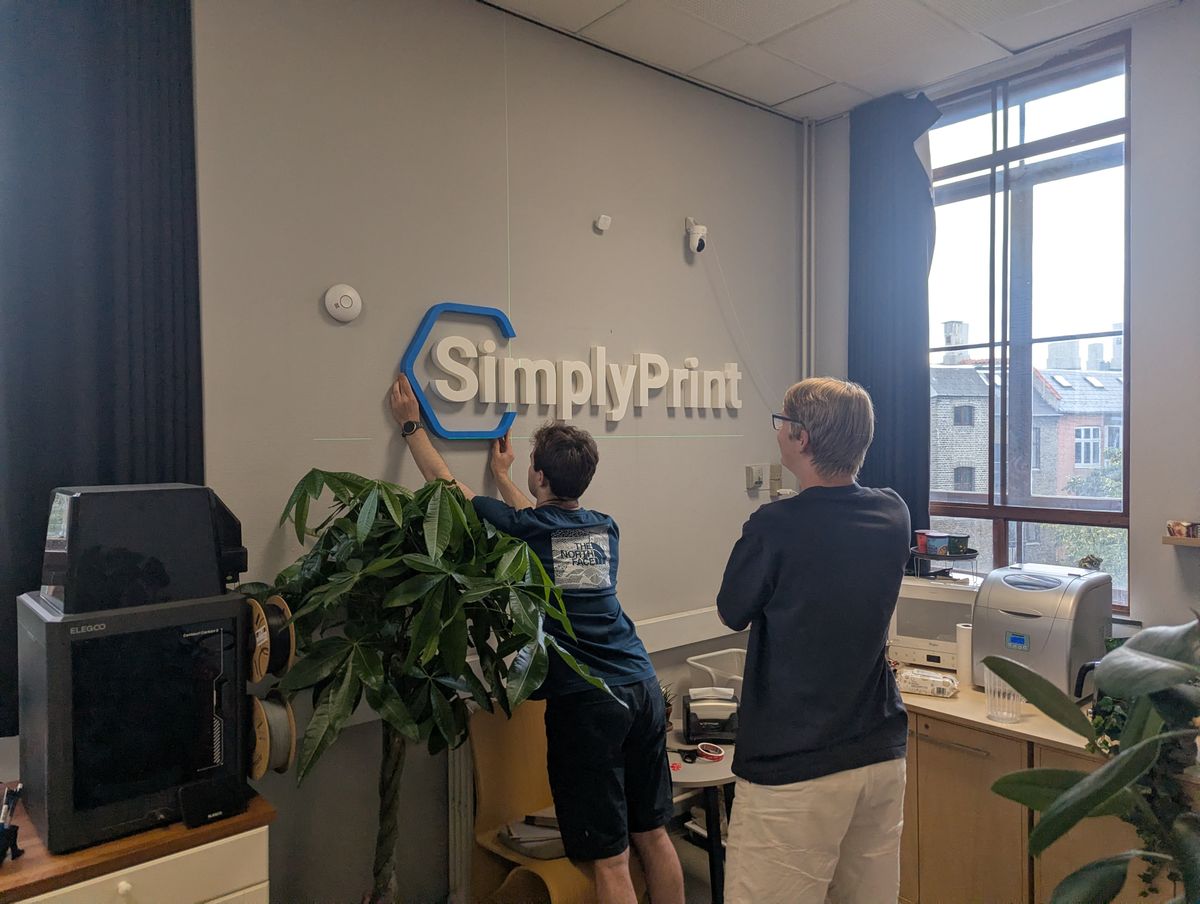 Mounting the 3D-printed SimplyPrint sign on the office wall